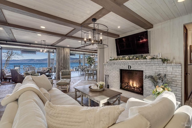 living room with a chandelier, a brick fireplace, beam ceiling, and recessed lighting