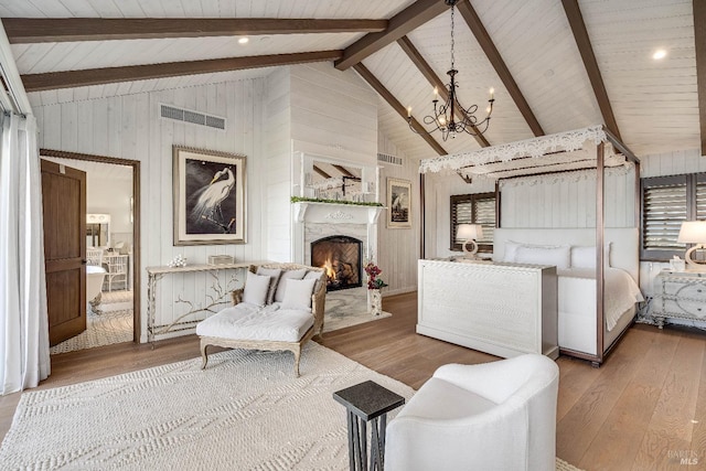 bedroom with beam ceiling, visible vents, a premium fireplace, and wood finished floors