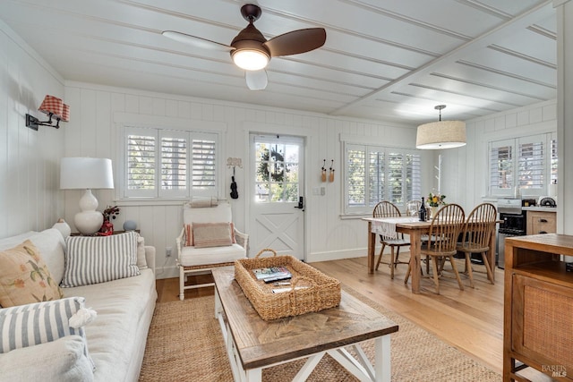 living room with light wood-type flooring, a ceiling fan, and baseboards