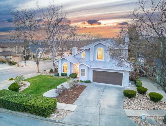 view of front of property with concrete driveway, a shingled roof, an attached garage, and a front yard