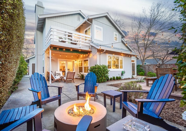 rear view of house featuring a balcony, an outdoor fire pit, fence, and a patio