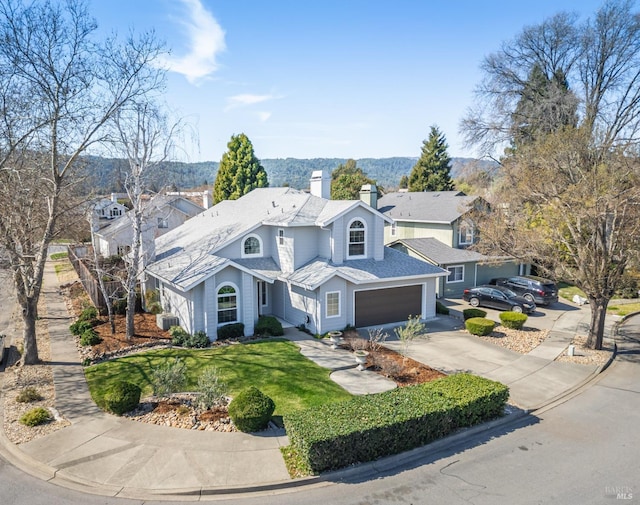 traditional home featuring a garage, concrete driveway, a chimney, and a front lawn