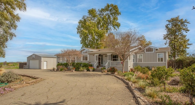 ranch-style home with a garage, driveway, covered porch, and an outdoor structure