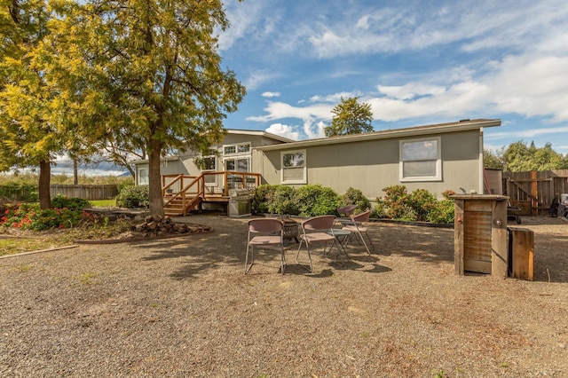 back of property with fence, a deck, and a patio