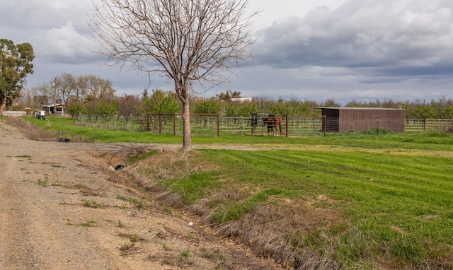 view of yard with fence, a rural view, an outdoor structure, and an exterior structure