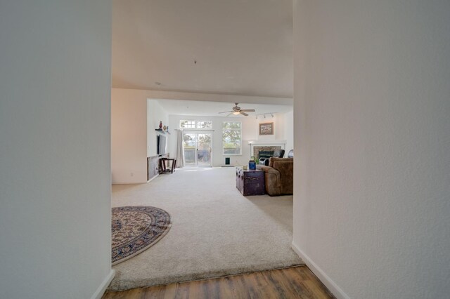 corridor featuring wood finished floors, baseboards, and carpet