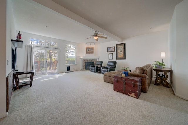 living room featuring ceiling fan, a stone fireplace, baseboards, beam ceiling, and carpet