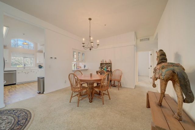 dining space with a towering ceiling, visible vents, a chandelier, and light colored carpet