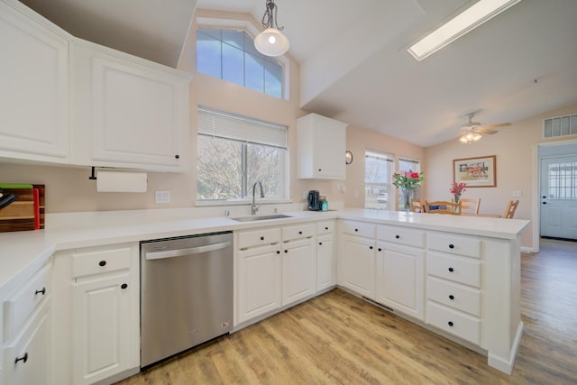 kitchen featuring lofted ceiling, light wood-style flooring, a peninsula, a sink, and dishwasher