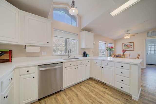 kitchen with lofted ceiling, dishwasher, a sink, light wood-type flooring, and a peninsula