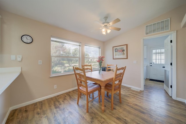 dining space with a ceiling fan, wood finished floors, baseboards, lofted ceiling, and visible vents