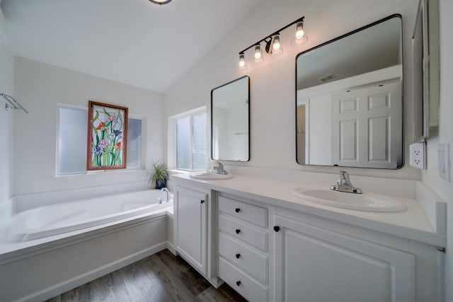 full bath with double vanity, a garden tub, vaulted ceiling, and a sink