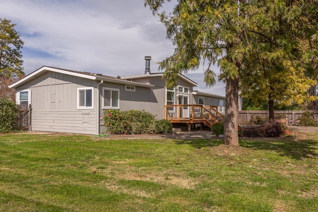 back of property with a wooden deck, fence, and a yard