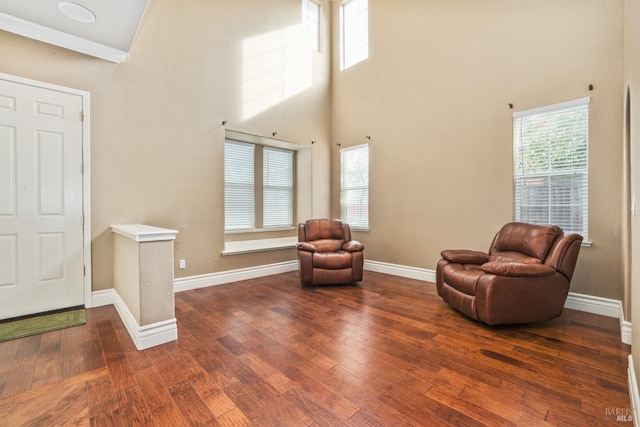 sitting room with hardwood / wood-style flooring, a high ceiling, and baseboards