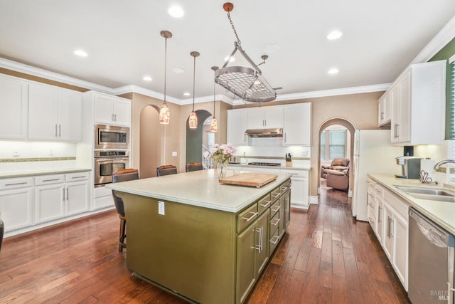 kitchen featuring arched walkways, stainless steel appliances, white cabinetry, a sink, and under cabinet range hood