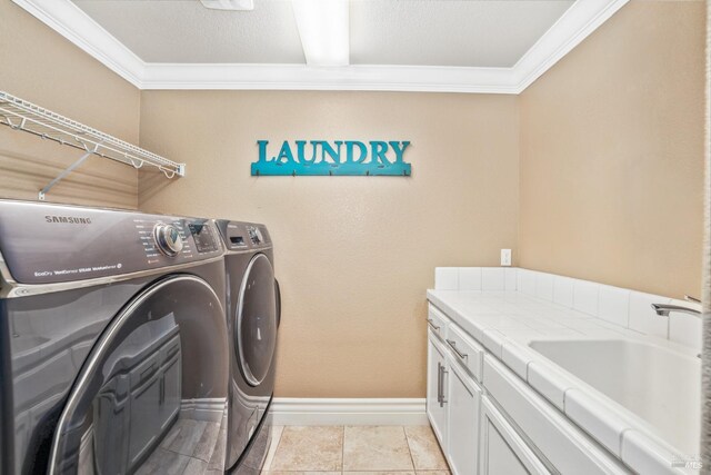 laundry area with a sink, baseboards, cabinet space, washer and clothes dryer, and crown molding