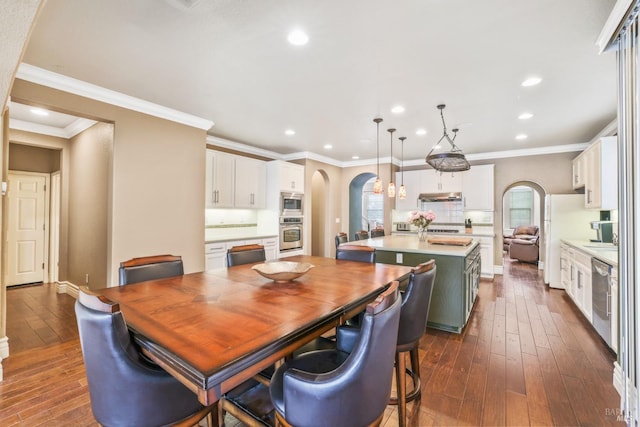 dining space with arched walkways, recessed lighting, baseboards, dark wood finished floors, and crown molding