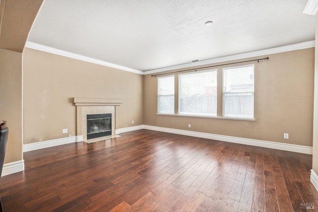 unfurnished living room featuring a tile fireplace, crown molding, baseboards, and hardwood / wood-style flooring