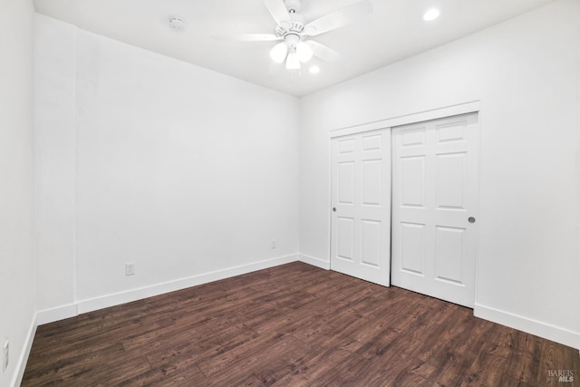 unfurnished bedroom featuring dark wood-style floors, ceiling fan, a closet, and baseboards
