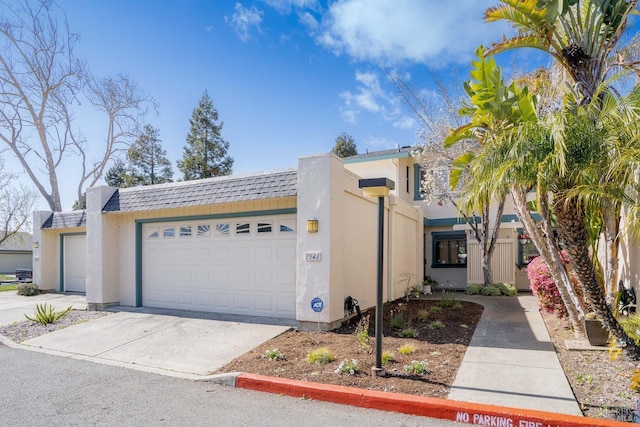 view of front facade featuring concrete driveway, a shingled roof, an attached garage, and stucco siding