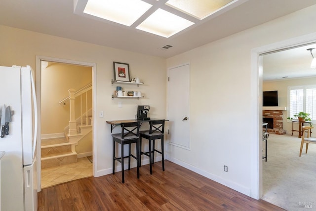 dining area featuring visible vents, stairway, a brick fireplace, wood finished floors, and baseboards