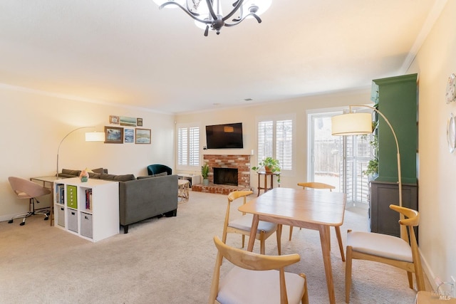 dining space featuring a brick fireplace, light carpet, crown molding, and a notable chandelier