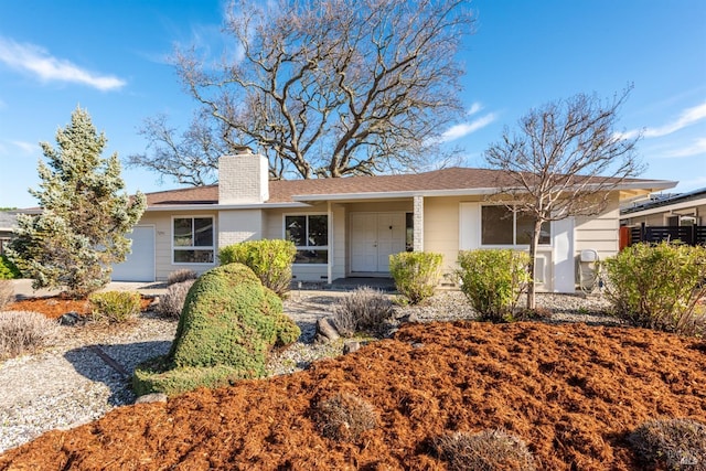 ranch-style house featuring a chimney and an attached garage