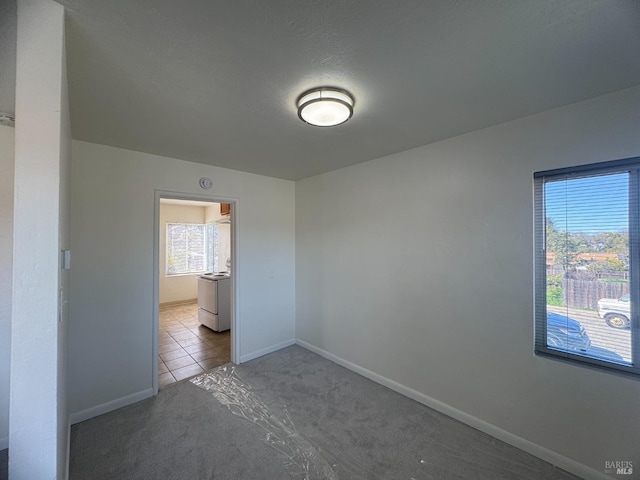 unfurnished bedroom featuring carpet, a textured ceiling, baseboards, and tile patterned flooring