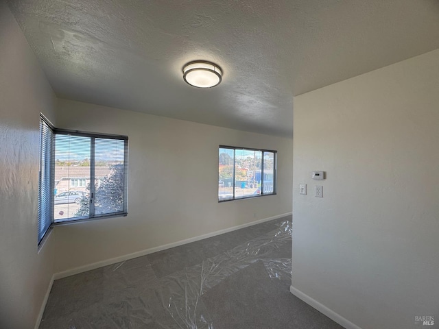 carpeted empty room featuring baseboards and a textured ceiling