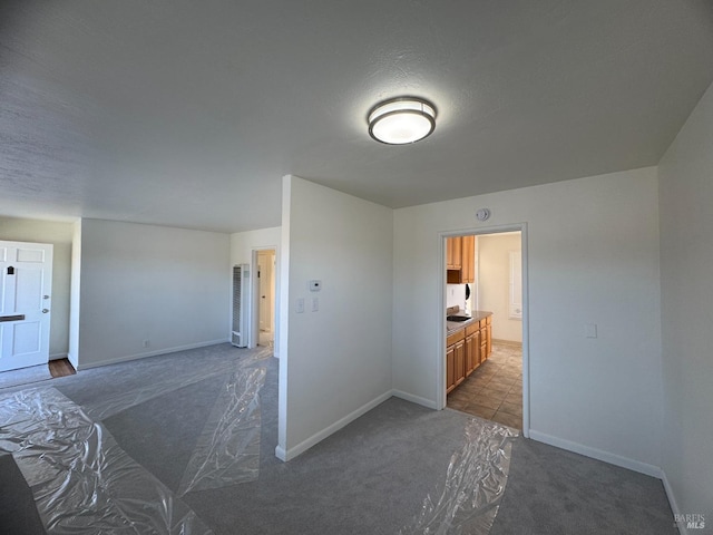 spare room with a textured ceiling, dark carpet, and baseboards