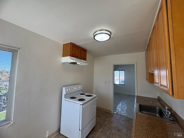 kitchen featuring under cabinet range hood, electric range, a sink, brown cabinetry, and dark countertops