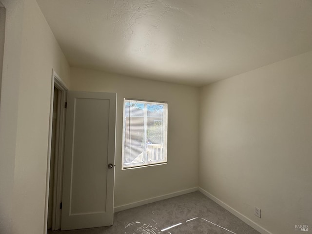 carpeted empty room with baseboards