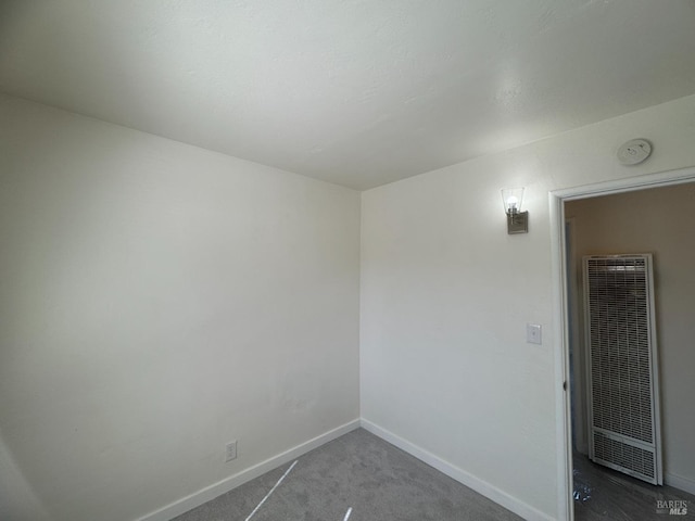 empty room with carpet, a heating unit, and baseboards