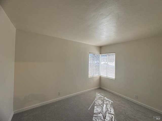 spare room with carpet, a textured ceiling, and baseboards