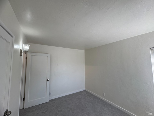 spare room featuring carpet floors and baseboards