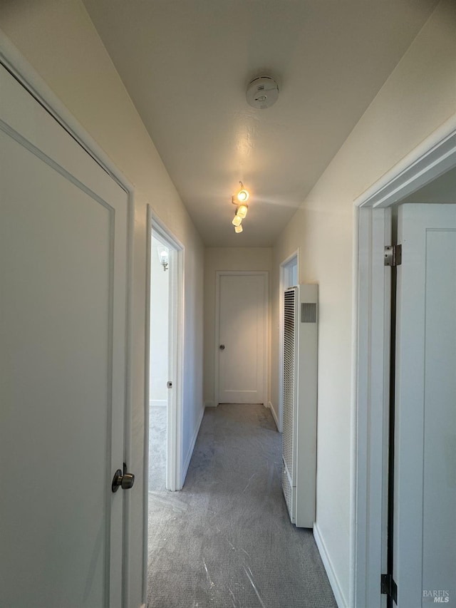 hall with a heating unit, carpet flooring, and baseboards