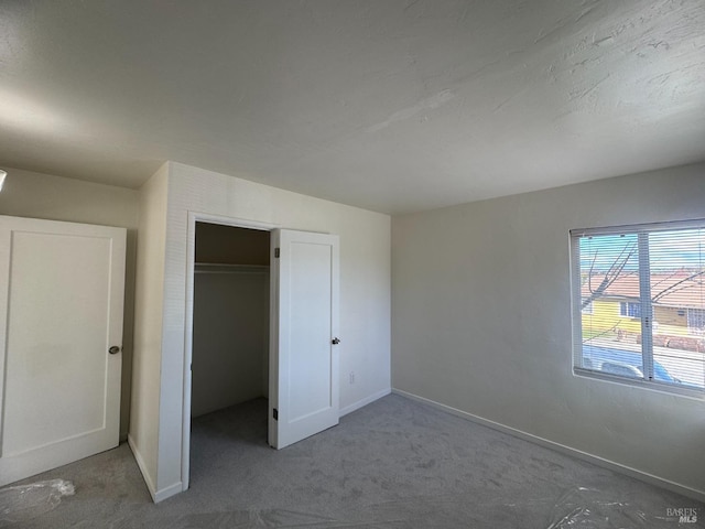 unfurnished bedroom featuring carpet floors, baseboards, and a closet