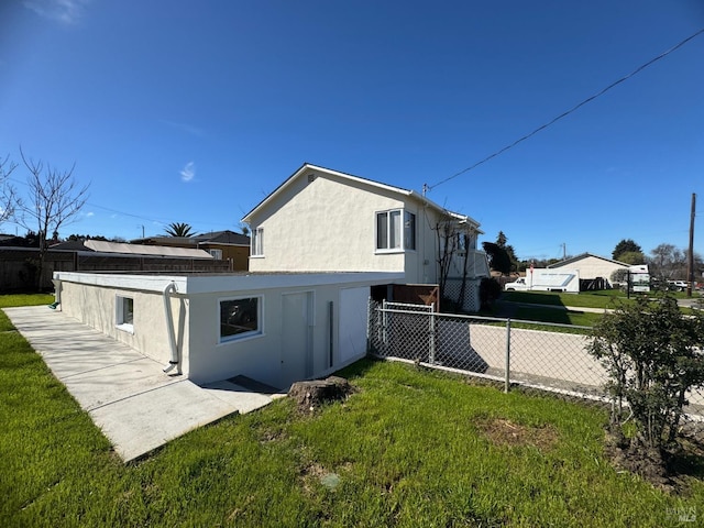 view of side of property featuring a yard, fence, and stucco siding