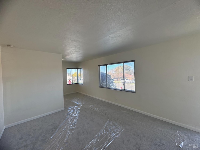 unfurnished room with baseboards and a textured ceiling