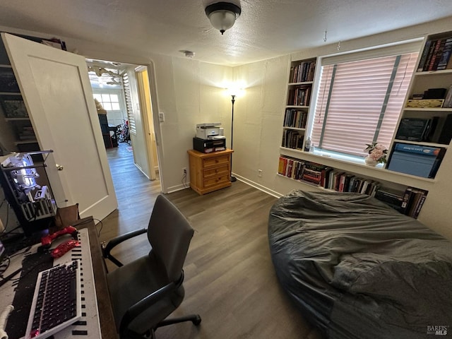 bedroom with a textured ceiling, baseboards, and wood finished floors