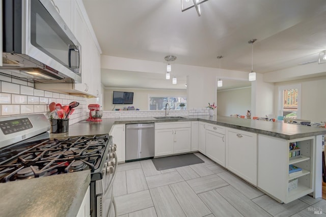 kitchen with stainless steel appliances, a sink, white cabinets, decorative backsplash, and pendant lighting