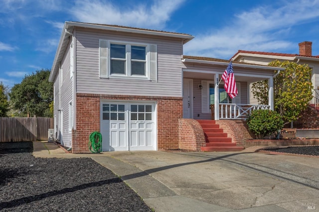 split level home featuring a porch, a garage, fence, and brick siding