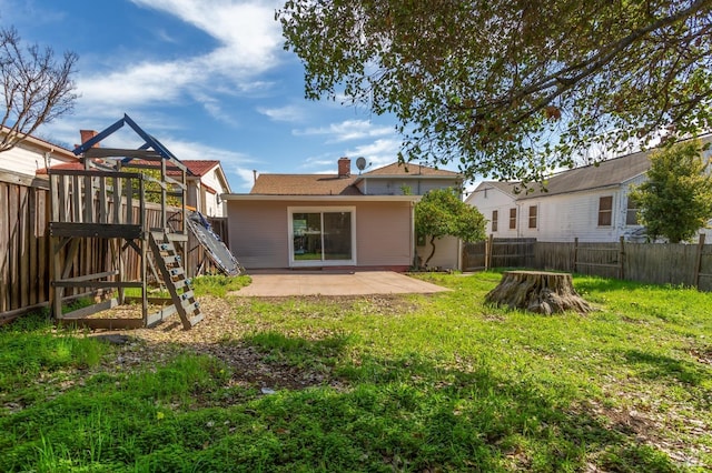 back of house featuring a playground, a patio, a yard, and a fenced backyard