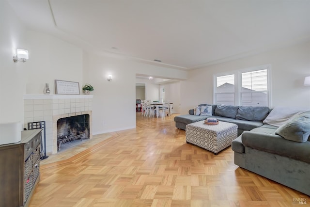 living room featuring a tile fireplace, visible vents, and baseboards