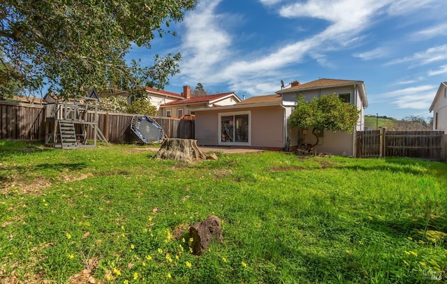 rear view of house with a yard and a fenced backyard