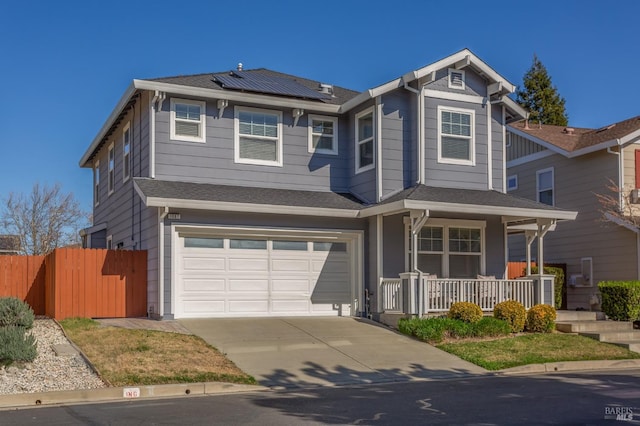 view of front of house featuring concrete driveway, an attached garage, fence, roof mounted solar panels, and a porch