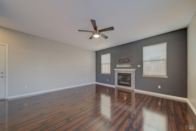 unfurnished living room with ceiling fan, a fireplace, wood finished floors, and baseboards