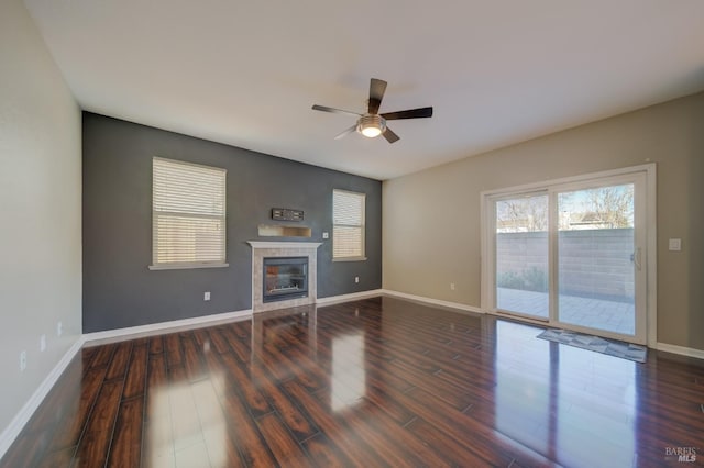 unfurnished living room featuring baseboards, ceiling fan, a tiled fireplace, and wood finished floors