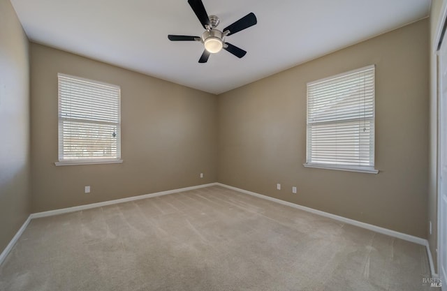 empty room with light carpet, a ceiling fan, and baseboards