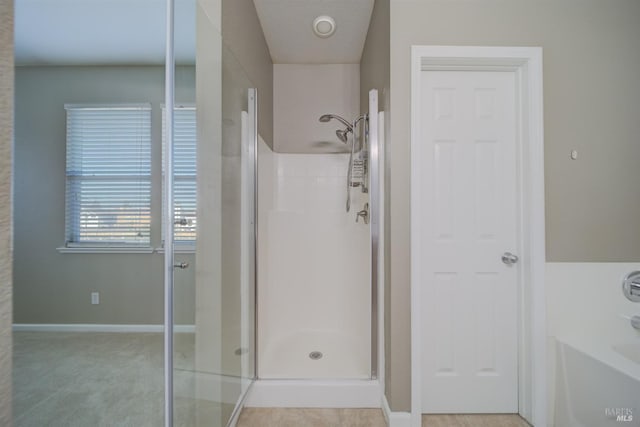 full bathroom featuring a stall shower, a bathtub, and baseboards